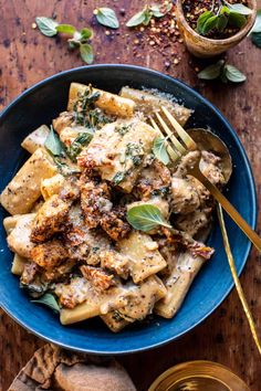 a blue bowl filled with pasta and meat covered in sauce next to some breadcrumbs