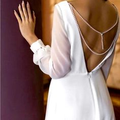 the back of a woman's white dress with pearls on her neck and shoulders