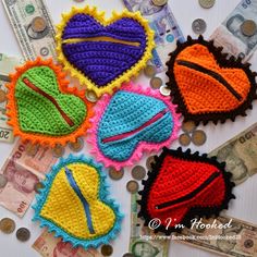 four crocheted heart shaped objects sitting on top of some money and cash bills