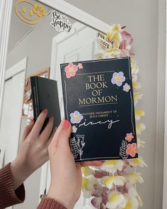 the book of mormon is being held by a woman's hand in front of a mirror