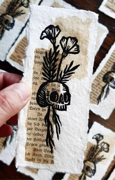 a hand holding up a piece of paper with flowers on it and words written in black ink