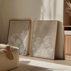 two framed pictures sitting on top of a wooden floor next to a chair and table