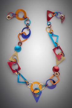 a multicolored necklace is displayed on a gray surface with an arrow shaped link