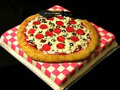 a large pizza sitting on top of a red and white checkered paper plate covered in toppings