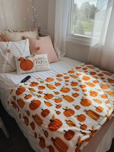 a white bed topped with lots of pillows next to a window covered in pumpkins