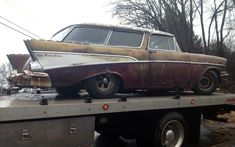 an old car is on the back of a flatbed truck