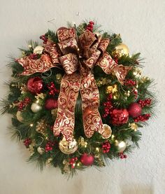 a wreath hanging on the wall decorated with christmas ornaments and bows, including baubles