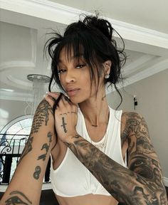 a woman with lots of tattoos on her arm and chest, posing for the camera