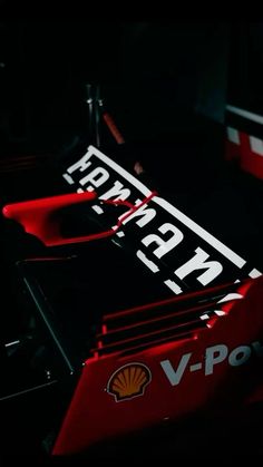 a close up view of the front end of a red and black race car with its lights on