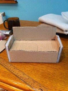 an open cardboard box sitting on top of a wooden table next to a measuring tape