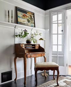 a room with a chair, desk and painting hanging on the wall above it's doorway