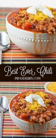 two bowls filled with chili and cheese on top of a striped table cloth next to spoons