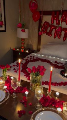 valentine's day table setting with candles and rose petals on the bed in front of it