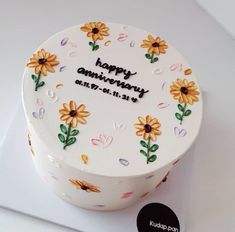 a birthday cake decorated with flowers and the words happy anniversary on it's side