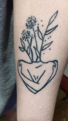 a black and white photo of a plant in a vase on someone's arm