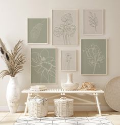 a white table topped with vases filled with flowers next to pictures on the wall