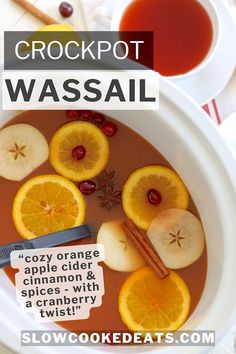 a bowl of crockpot wassail with oranges, apples and cinnamon