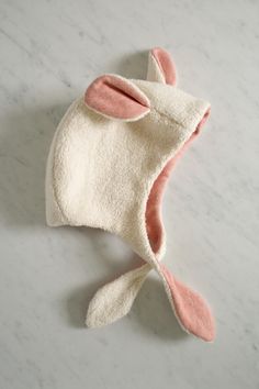 a white hat with pink ears on top of a marble countertop next to a pair of scissors