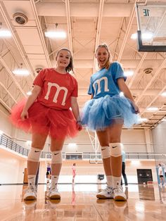 two girls dressed in costumes standing on a basketball court