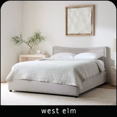 a bed with an open drawer underneath it in a room that has white walls and wooden floors