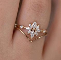 a woman's hand wearing a gold ring with white stones on it and a flower design