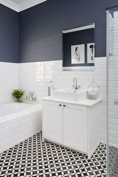 a bathroom with black and white tile flooring and walls, along with a bathtub