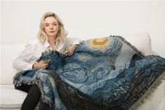 a woman sitting on a couch with a blanket over her face and the image of starry night