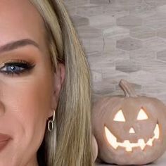 a woman with blonde hair and blue eyes is next to a carved pumpkin