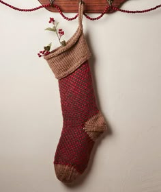 a knitted christmas stocking hanging from a wooden hanger on a white wall