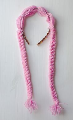 pink crocheted scarf with tassels hanging from it's ends on a white surface