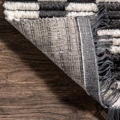 an area rug with fringes on top of wooden flooring next to a wall