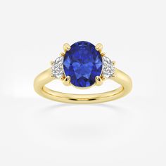 a yellow gold ring with a blue sapphire and two white diamonds on the side, set in