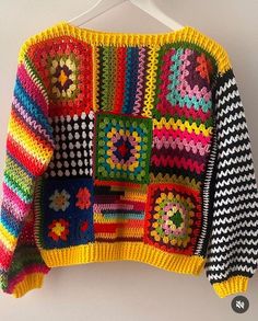 a multicolored sweater hanging on a white hanger with buttons and holes in it