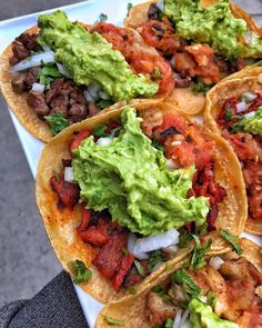 some tacos are sitting on a plate with guacamole and other toppings