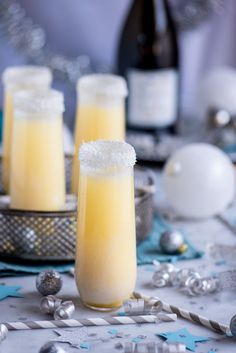 two tall glasses filled with yellow liquid on top of a table covered in confetti