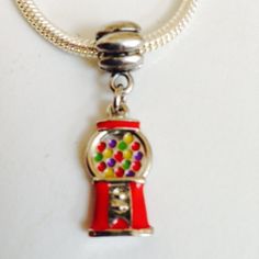 a red and silver charm with a gummy machine on it's front end