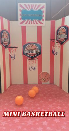 an indoor basketball court with three orange balls on the floor and two hoops in front of it