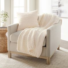 a living room with a couch, chair and basket on the floor in front of it