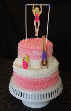 a pink and white cake with two girls on it's top, one is upside down