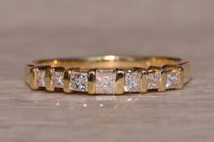 a gold ring with five princess cut diamonds