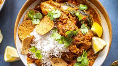 a bowl filled with rice, meat and cilantros on top of a blue table