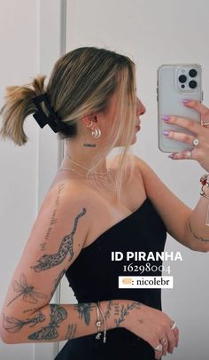 a woman taking a selfie in front of a mirror with tattoos on her arm