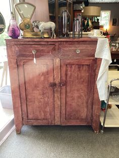 an old wooden cabinet with some items on top of it and a lamp in the background