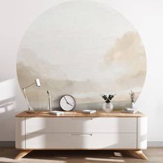 a living room with a large round mirror on the wall next to a white dresser