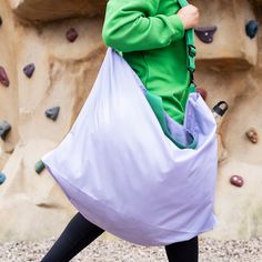 a woman carrying a large bag in front of a climbing wall