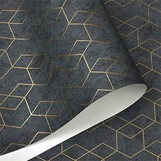 a white knife sitting on top of a black and gold patterned table cloth next to a roll of paper