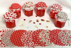 red jars filled with candy sitting on top of a table next to hearts and flowers