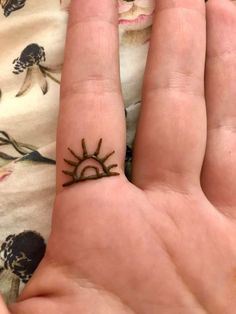 a person's hand with a small sun tattoo on their left thumb and finger