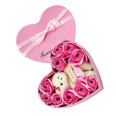 a heart shaped box filled with pink roses and a teddy bear in the center,