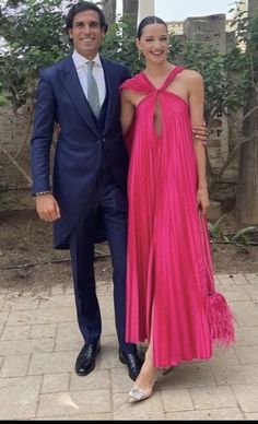 a man in a suit and tie standing next to a woman wearing a pink dress